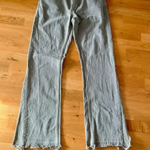 Beige flared jeans från Zara - Beiga flared jeans från Zara med bootcut passform och råa, fransiga benslut. Klassisk femficksmodell med bälteshällor och dragkedja. Tillverkade i bomullstyg, perfekta för en avslappnad och trendig look. Storlek EUR 40. Djur- o rökfritt hem. 