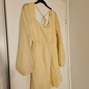 Ljusgul klänning från Nelly - Supersöt ljusgul kortklänning från Nelly med långa puffärmar och snygg knytning i ryggen. Storlek 38. Aldrig använd, prislappen finns kvar. Jättefin modell men säljer då den tyvärr är för stor för mig. 