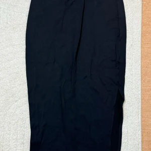 Svart kjol med slits från SHEIN - Svart medel långkjol från SHEIN i storlek S. Kjolen har en rak passform och en snygg slits på sidan.