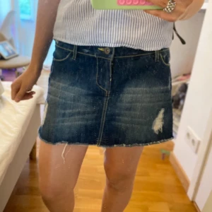 Mörkblå jeanskjol från Calzedonia - En mörkblå kjol med gul och hål. Men trådar som hänger ner