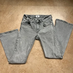 Grå bootcut jeans från 157 - Snygga grå jeans från 157 med bootcut-modell och låg midja. Storlek S short length. Jeansen har klassisk femficksdesign, dragkedja och knapp framtill. Materialet är jeans i bomull och de har en stilren, ljusgrå tvätt som passar till det mesta.