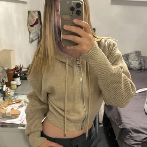 Beige stickad hoodie från zara - Supermysig beige stickad hoodie från Zara med dragkedja framtill och snörning i huvan. Croppad modell med ribbade muddar och ärmar. Perfekt för lager-på-lager och chill dagar.