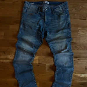 Jack & Jones Skinny Liam jeans blå - Säljer ett par blå skinny jeans från Jack & Jones, modell Liam. Jeansen har klassisk femficksdesign, smal passform och snygga slitningar framtill. Tillverkade i stretchig denim för extra komfort. Perfekta för dig som gillar en tajt look.