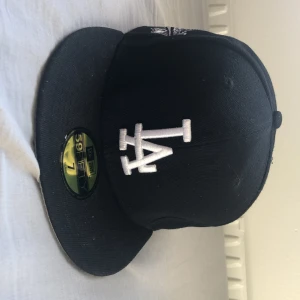 LA Dodgers 59FIFTY keps svart  - En Snygg LA Dodgers 59FIFTY keps från New Era i svart. Den  har broderad LA-logga framtill och 1988 World Series-märke på sidan. Klassisk flat peak och MLB-logga bak. Perfekt för dig som gillar streetwear och sportig stil. Ny pris 500-600 