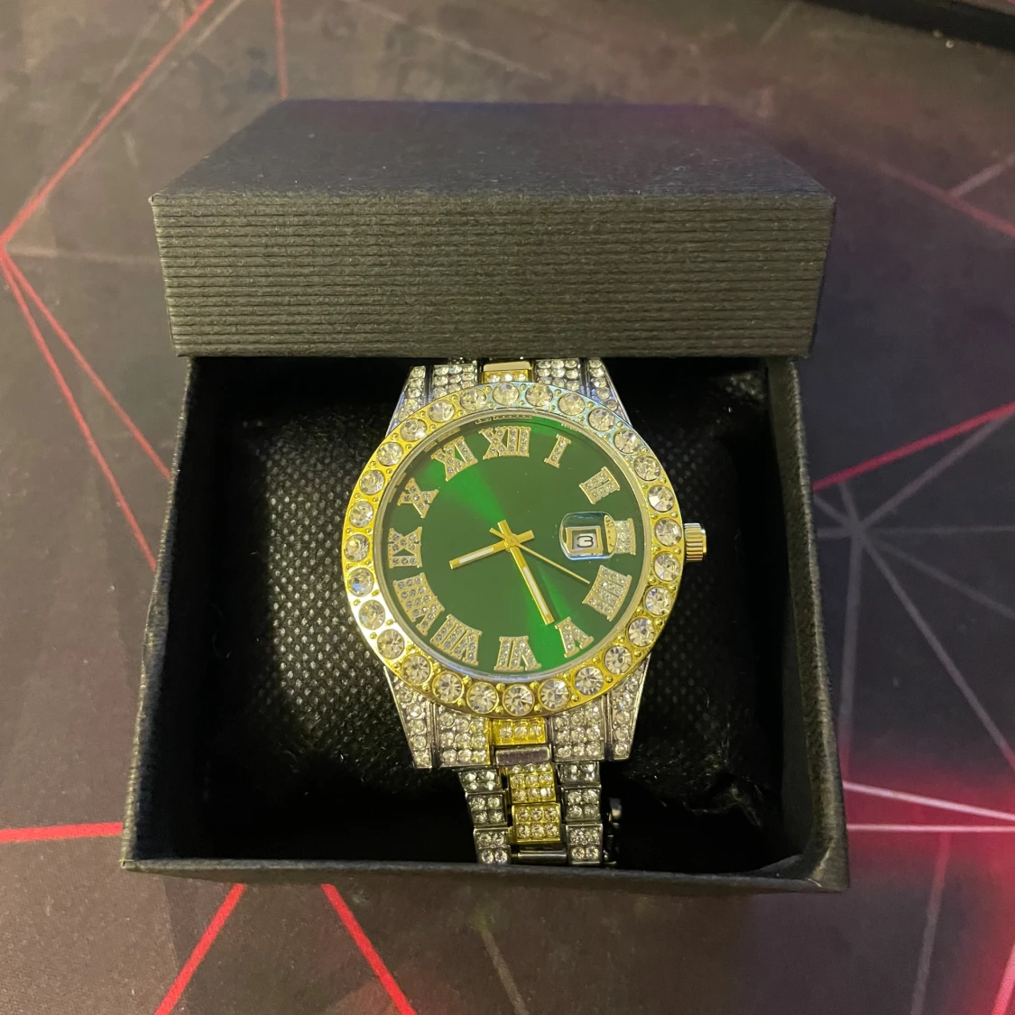 Grön och guldig klocka med stenar