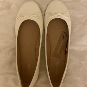 Vita ballerinaskor från Anna Field - Snygga vita ballerinaskor från Anna Field med rund tå och söt rosettdetalj framtill. Skorna är tillverkade i återvunnen polyester och har en platt sula i brunt. Perfekta för dig som gillar stilrena och klassiska skor med en feminin touch. Kom jätte gärna med prisförslag!!!!