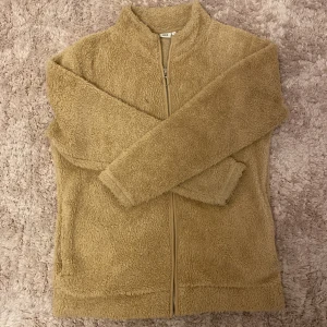Beige fleecejacka med dragkedja - Mysig beige fleecejacka med hel dragkedja och ståkrage. 🧸 Jackan är fluffig och har två fickor framtill. Perfekt för mindre kyliga dagar när du vill vara både gosig och snygg! Långärmad och i mjukt syntetmaterial. 🤍 Säljer pga att den ej kommer till användning längre då jag har tröttnat på den :( Har används flertal gånger men inget spår av att den är använd! 