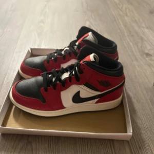 Nike Air Jordan 1 Chicago sneakers - Säljer ett par Nike Air Jordan 1 Chicago sneakers i rött, svart och vitt skinn. Klassisk high-top modell med svart swoosh, perforerad tå och svart snörning. Perfekta för dig som vill ha en tidlös streetwear-look.