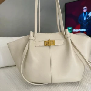 Vit handväska från Gina Tricot - Snygg vit handväska med stilren form och guldfärgat spänne framtill. Väskan har långa axelband och rymligt innerfack med dragkedja. Materialet är slätt syntet och designen är enkel men trendig, perfekt för dig som gillar minimalistisk stil. Storleken ser ni på sista bilden. Aldrig använd!!