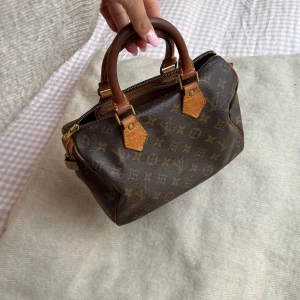 Louis Vuitton Speedy 25 väska - Väska från Louis Vuitton Speedy i storlek 25 Självklart äkta och inköpt på Soleplus! Mycket sparsamt använd och är i överlag i fint skick. Det finns inga fläckar inuti och dragkedjan fungerar utmärkt. Det finns en slitning på handtaget som visas på bild 5 men eftersom väskan bärs med motsatts håll mot slitningen så är det inget som "dras ned" och påverkas mer av användningen. Detta går att åtgärda utan problem hos en skräddare. Kontakta mig för fler bilder eller frågor och lämna gärna bud! 🥰💘