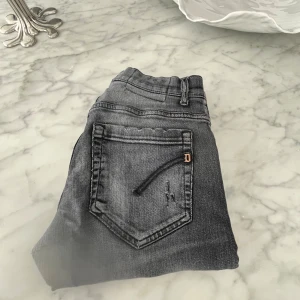 Svarta jeans från dondup, stl 30 - Tjena dessa jeans är från dondup och passar perfekt för dig som vill ha lite klass i din stil. Dem har lite slitningar runt benen och är lite mörk grå. 