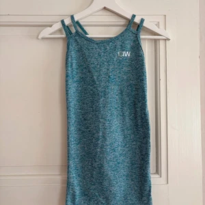 Turkos linnetopp från ICANIWILL - Säljer en turkos linnetopp från ICANIWILL med smala axelband och snyggt korsad rygg. Toppen har ett melerat mönster och är tillverkad i mjuk, stretchig polyester som andas. Perfekt för träning och sportiga dagar. Snygg detalj med öppning i ryggen och ventilerande hålmönster.