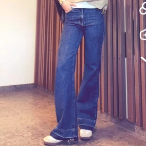 Mörkblå bootcut jeans med breda ben - Snygga mörkblå jeans med bootcut och breda ben. De har en stor sömn nedtill som man ser på bild 1 och 2, men på första bilden sprättade jag upp den delen för att få en snygg detalj. Sen har jag limmat upp det igen som man lätt kan sprätta ner för för att kunna variera hur jag velat ha jeansen. Jag är178cm lång. Dessa är använda 5 gånger och köpte nypris för 1200kr