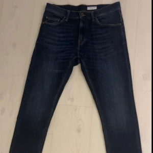 Tiger of Sweden mörkblå jeans Pistolero - Mörkblå jeans från Tiger of Sweden, modell Pistolero. Klassisk femficksdesign med snygga slitningar framtill och kontrastsömmar. Jeansen har rak passform och är tillverkade i bomullsdenim. Perfekta för dig som gillar stilrena och tidlösa jeans.