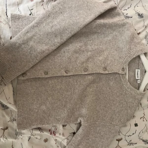 Beige kofta från Kappahl XS - Mysig beige kofta från Kappahl i storlek XS. Koftan är stickad med rund halsringning, ribbade muddar och knappar framtill. Perfekt för lager-på-lager och chill dagar. Enkel och stilren design som funkar till allt.