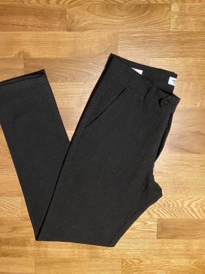  Jack & Jones byxor  - Snygga bruna byxor från Jack & Jones med diskret rutmönster. Klassisk rak passform. Byxorna har fickor både fram och bak, perfekta för en stilren look. Materialet känns mjukt och har en lätt stretch.                                                  Byxorna är knappt använda, de ser ut som nya.    Innerbenslängd är 80 Ytterbenslängd är 105