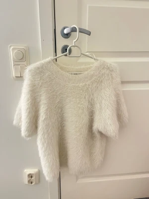 Vit fluffig stickad tröja Wera XS - Vit fluffig stickad tröja från Wera i storlek XS. Tröjan har korta ärmar och rund halsringning. Inte använd så många gånger. Normal i storleken. 