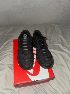 Nike Air Max Plus Triple Black -     Äkta Nike Air Max Plus (TN) i svart färg. Använda 2 gånger men i väldigt bra skick. Original Nike-kartong medföljer.  Säljer ett par Nike Air Max Plus i helsvart färg. Skorna har den klassiska Tn-loggan bak, mesh och syntetmaterial på ovandelen samt synliga Air-enheter i sulan. De har snörning och en sportig, chunky siluett som verkligen sticker ut. 