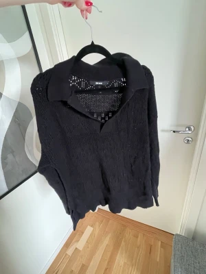 Svart stickad tröja  - Svart stickad tröja från BikBok med krage och v-ringning. Tröjan har ett genombrutet mönster och långa ärmar