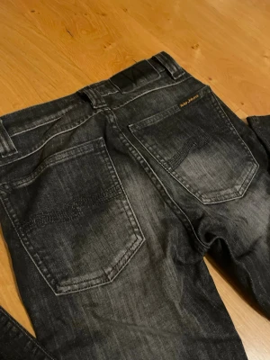 Svarta Nudie Jeans Skinny W24 L32 - Säljer ett par svarta skinny jeans från Nudie Jeans i storlek W24 L32. Jeansen har klassisk femficksdesign, svarta sömmar och en snygg tvättad look. Materialet är jeans och passformen är tight med smal siluett. Perfekt för dig som gillar stilrena och moderna jeans. Jag kan fixa snygga par slitningar men BARA om ni köper de först.