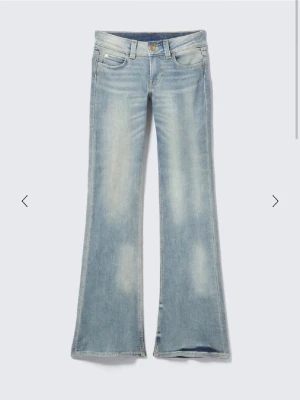 Ljusblå bootcut jeans - Säljer ett par ljusblå bootcut jeans med klassisk femficksdesign och låg midja. Jeansen har en snygg tvättad look och är tillverkade i mjukt denimtyg. Perfekta för dig som gillar retrovibbar och vill ha ett par jeans med lite vidare ben.