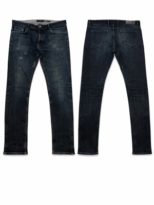 Massimo Dutti slim fit blå jeans - Slim fit jeans från Massimo Dutti i mörkblå tvätt med slitningar och distressed detaljer. Klassisk femficksmodell med knappgylf och smal passform. Tillverkade i bomull med en snygg faded effekt på låren och knäna.