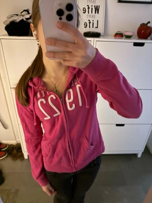 Hollister hoodie zip up vintage rosa  - Vintage Hollister huvtröja med dragkedja i en unik rosa färg. Storlek M men passar en vanlig S bättre! I toppskick! Har den vita Hollister-logotypen på bröstet. 