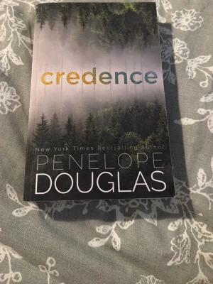 Credence - Upptäck 'Credence' av Penelope Douglas – en bok som lockar med mystik och dramatik. Perfekt för dig som gillar spännande berättelser och vill ha något som sticker ut i bokhyllan. Omslaget ger en känsla av äventyr i vild natur.