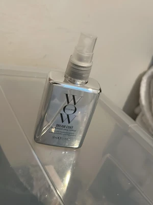Color Wow Dream värmeskydd 50ml - Color Wow Dream Coat Supernatural Spray i en silvrig plastflaska med spraymunstycke. Flaskan rymmer 50 ml och har en modern, metallisk look. Produkten är känd för att ge glans och skydda mot fukt. Perfekt för dig som vill ha ett fräscht och stylat hår.