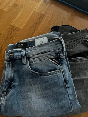 Replay jeans i blått och svart - Två par Replay jeans, ett par i ljusblå tvätt och ett par i mörkgrått. Klassisk femficksmodell med Replay-logga på fickan. Snygg passform och mjukt jeansmaterial som är sköna att bära hela dagen.