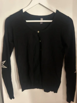 Svart kofta - Säljer denna fina koftan med stjärnor på armbågarna, koftan är som nyskick då den bara används en gång. 