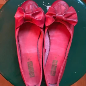 Röda ballerinaskor med rosett  - Säljer ett par söta röda ballerinaskor från XIT med rosett framtill. 