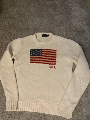 Ralph lauren tröja - Säljer en riktigt snygg och stilren stickad Ralph lauren tröja med en amerikansk flagga. Den passar dig som är mellan 155-170 cm lång.  Skriv gärna om du har frågor!