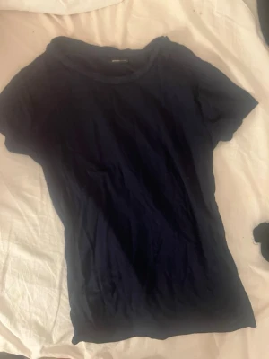 Svart basic t-shirt i bomull - En enkel blå t-shirt med rund hals och korta ärmar. Tillverkad i mjuk bomull, perfekt för en clean och avslappnad stil. Passar till allt och är ett måste i garderoben. Den e tight 