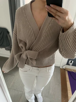 Beige omlottstickad tröja med knyt - Säljer en beige stickad tröja i omlottmodell som går att knyta själv💕endast använd en gång, köpt på en marknad så vet tyvärr inte märket 