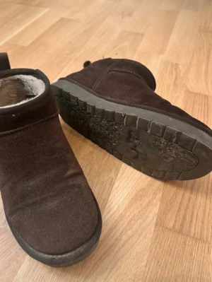 Bruna mockastövlar med foder - Mysiga bruna stövlar i mocka med mjukt foder på insidan och grov sula. Perfekta för kalla dagar och enkel att dra på tack vare den låga modellen. Snygg och enkel design som passar till det mesta.