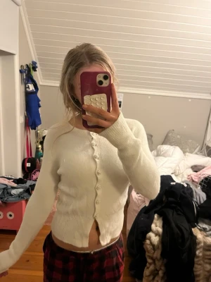 Vit kofta från Zara med pärlknappar - Supersöt vit kofta från Zara med rund halsringning och dekorativa pärlknappar. Koftan är ribbstickad vid ärmslut och nederkant, har lång ärm och är i mjukt, stickat material. Perfekt att slänga över en topp för en trendig look.