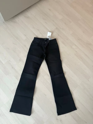 Svarta bootcut jeans från Only - Snygga svarta jeans från Only med bootcut-modell och lågmidjat . Jeansen har dragkedja och knapp framtill samt är tillverkade i ett mjukt jeansmaterial som sitter skönt. Perfekta för dig som gillar en tidlös look med lite vidare ben.