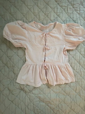 Ljusrosa topp - Säljer en ljusrosa topp med rosetter framtill!