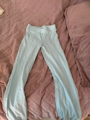 Ljusblå mjuka loungebyxor - Supersköna ljusblå loungebyxor med bred resår i midjan och raka ben. Perfekta för att chilla hemma eller mysa runt i. Materialet känns tunt och stretchigt för extra komfort.Det är barn storlek 152 och lite genomskinliga.