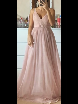 Ljusrosa långklänning från Nelly - Elegant ljusrosa långklänning med v-ringning och smala axelband från Nelly. Klänningen har ett markerat midjeband med dekorativt spänne och ett flytande, svepande tyg i flera lager. Perfekt för speciella tillfällen och ger en romantisk look.  Passar både xs och xxs. Har använts endast på ett tillfälle. Om det önskas fler bilder är det bara att höra av sig! Köparen står för frakten 🩷