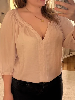 Ljusrosa blus med v-ringning - Söt ljusrosa blus med djup v-ringning och avslappnad passform. Blusen har trekvartsärm och är tillverkad i ett lätt, vävt tyg som ger en luftig känsla och glans. Perfekt att styla med jeans eller kjol och går att klä upp och ner. Tröjan är från H&M originellt. 💞