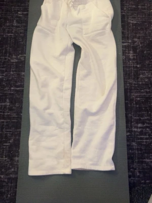 Vita mjukisbyxor med snörning - Säljer ett par vita mjukisbyxor med snörning i midjan och två fickor framtill. Byxorna har en avslappnad passform och är perfekta för en chill stil. Tillverkade i mjukt material som känns skönt mot huden.