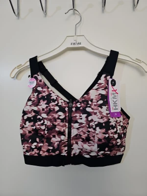 Mönstrad sport-bh från Hunkemöller - Sport-bh från Hunkemöller med blommigt mönster i rosa, svart och vitt. Bh:n har breda axelband, dragkedja framtill och är tillverkad i ett stretchigt funktionsmaterial. Perfekt för träning med hög support och bekväm passform.