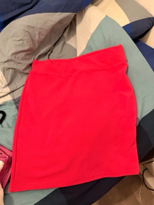 Knallrosa kortkjol i bomull - Säljer en enkel och snygg knallrosa kortkjol i mjukt bomullstyg. Kjolen har en rak passform och är perfekt för dig som vill ha en färgklick i garderoben. Passar till många olika stilar och är lätt att matcha med både toppar och tröjor.