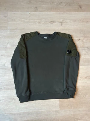 Grön CP Company Crewneck Tröja - Fin CP Company tröja i grön färg. Tröjan är i mycket bra skick och sparsamt använd. |  Äkta som allt annat jag säljer! ✅|  Storlek: 14 =S| Skick: Mycket Bra Skick | Färg: Mörkgrön | Märke: C.P Company | Modell:  crewneck, tröja |  Mått: | Längd: 64 cm | Bröstvidd: 52 cm |  Hör gärna av dig vid frågor så svarar jag så fort jag kan! 🙂  