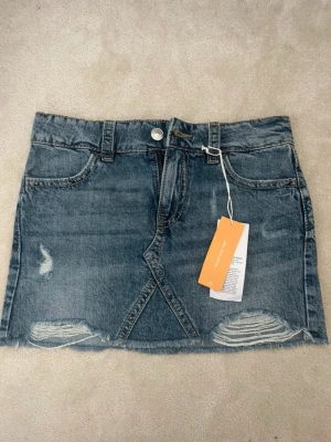 Blå jeanskjol med slitningar - blå jeanskjol från gina. aldrig använd!! skriv för fler bilder.