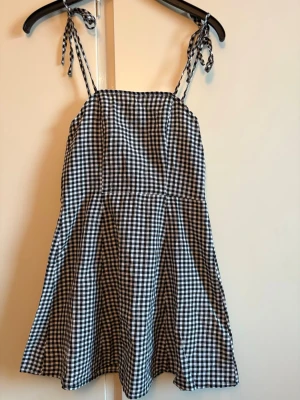 Rutig klänning  - Rutig klänning med dragkedja baktill. Axelbanden knyter man som man vill. Aldrig använd 