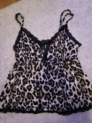 Leopardmönstrad linnetopp Gina Tricot - Säljer en leopardmönstrad linnetopp från Gina Tricot med tunna axelband och spetsdetaljer längs ringningen och nederkanten. I storlek S!