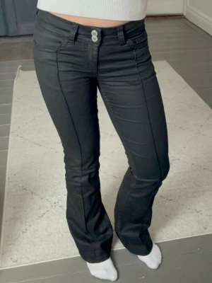 Svarta bootcut jeans med söm - Snygga svarta jeans med bootcut-modell och markerad söm framtill. Jeansen har hög midja, två knappar i linningen och klassiska fickor. Perfekta för dig som vill ha en trendig och bekväm passform.